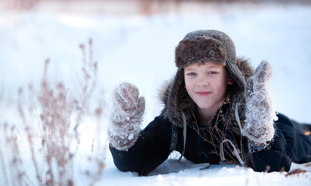 de jongen ligt in de sneeuw en kijkt naar de camera