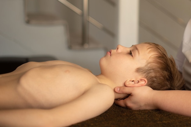 De jongen ligt op de massagetafel en de osteopaat regelt zijn schedelbeenderen