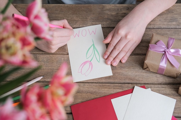 De jongen maakt een kaart voor moederdag Kindertekeningen