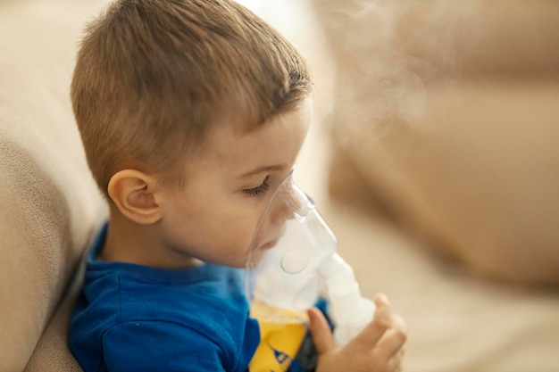 Foto de jongen maakt inhalatie met een vernevelaar die medicijnen in zijn longen inademt