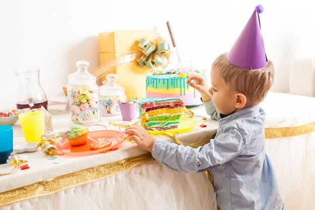 De jongen met de verjaardagshoed wil deze lekkere taart proberen