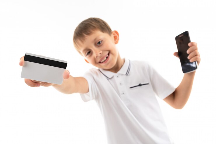 De jongen met een telefoon in zijn hand houdt een creditcard met een model op wit stand