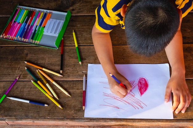 De jongen schilderde op wit papier met houtkleur