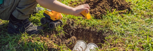 De jongen speelt recycling, hij begraaft plastic wegwerpschalen en biologisch afbreekbare borden banner lang