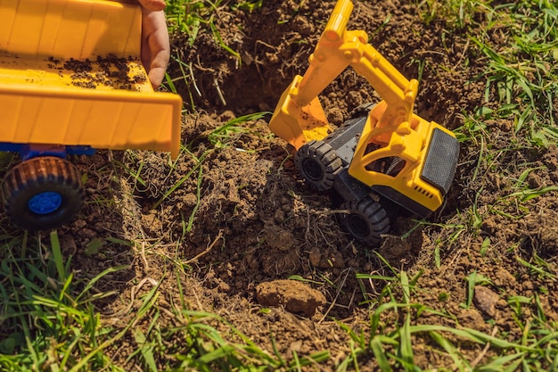 De jongen speelt recycling, hij begraaft plastic wegwerpschalen en biologisch afbreekbare borden