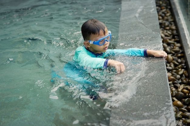 De jongen speelt water alleen naast pool in de zomerconcept
