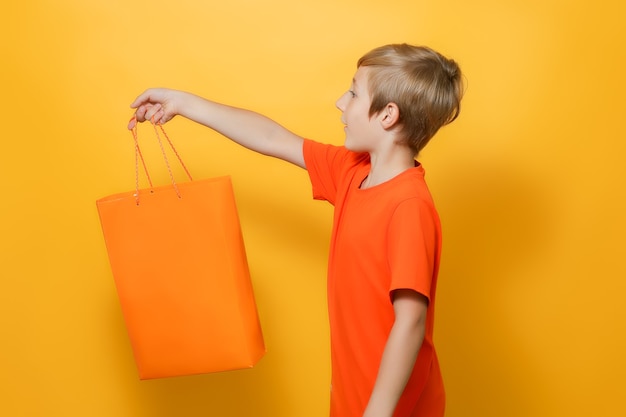 De jongen strekte zijn hand uit naar de zijkant waarin hij een oranje boodschappentas vasthoudt