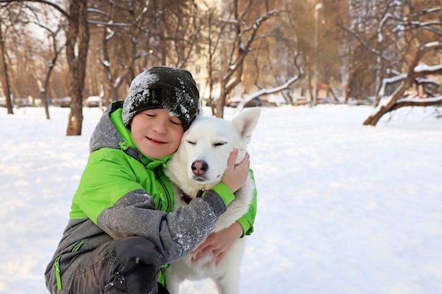 De jongen toont tederheid voor zijn geliefde hond in de winter in de natuur.