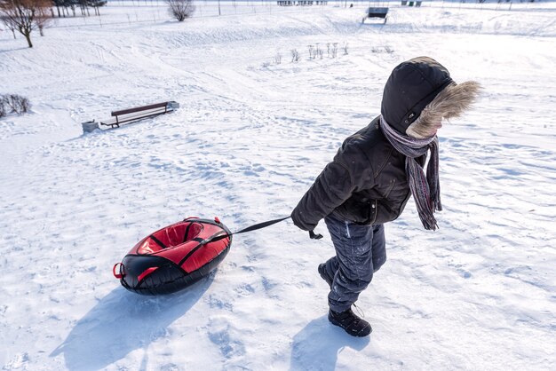 De jongen trekt een buis in de winter