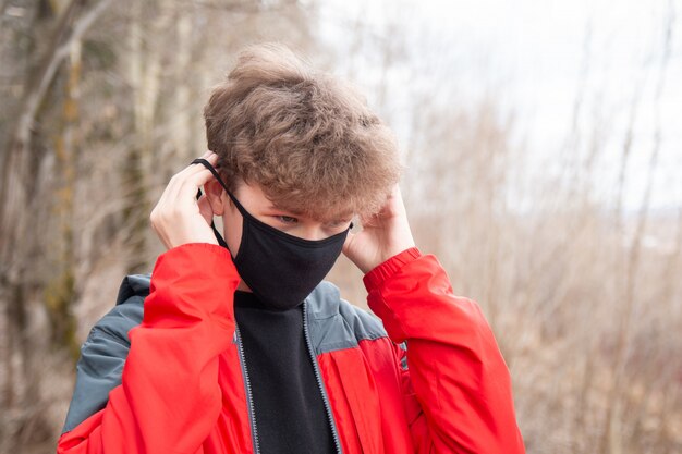 De jongen zet een zwart gezichtsmasker op.