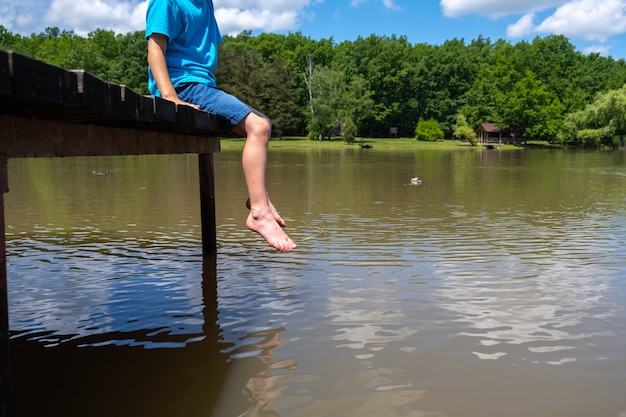 De jongen zit op de pier