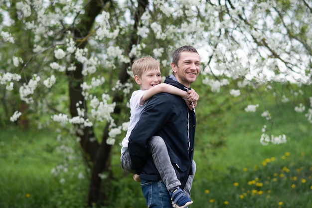 De jongen zit op papa's rug en ze lachen