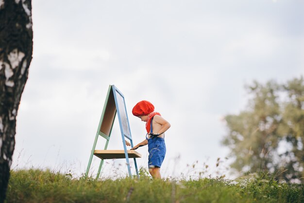 De jongenskunstenaar in de natuur maakt een tekening