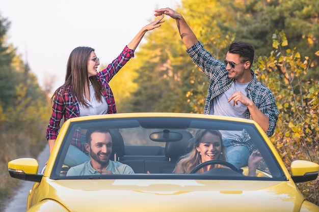 De jongeren reizen in een gele cabriolet