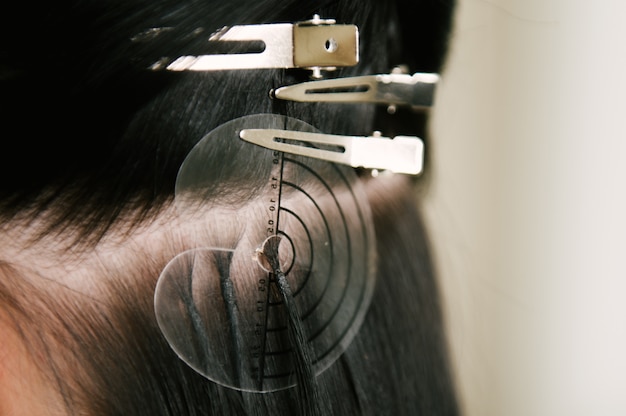 De kapper doet haarextensies aan een jong meisje in een schoonheidssalon. Professionele haarverzorging.