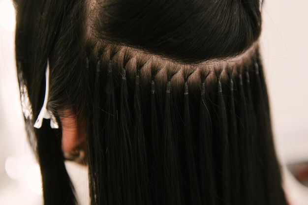 De kapper doet hair extensions aan een jong meisje in een schoonheidssalon Professionele haarverzorging Close up van capsules en strengen van volwassen haar