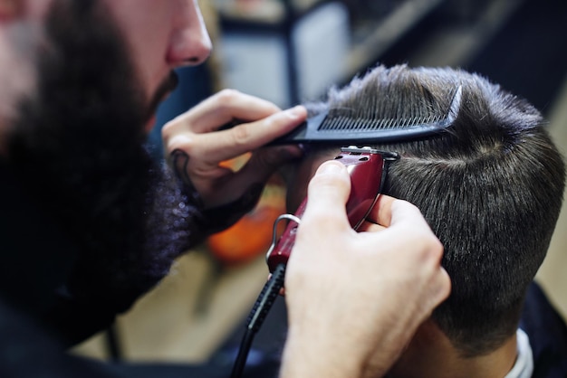 De kapper laat de man afscheid nemen van de klant een elektrische trimmer in een kapperszaak