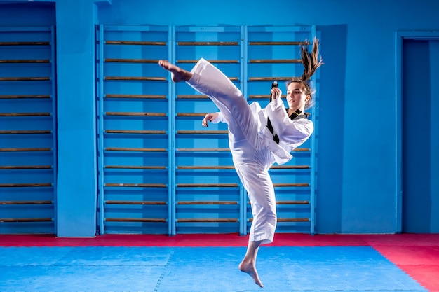 De karatevrouw met zwarte band Sportvrouw vechtende poses punch in sportuniform jurk Taekwondo karate