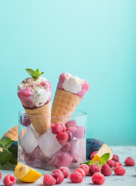 De kegelclose-up van het roomijs. Roze Roomijslepel in wafelkegel over blauwe achtergrond. Aardbei of frambozensmaak Zoet dessert dat met kleurrijk wordt bestrooid, close-up