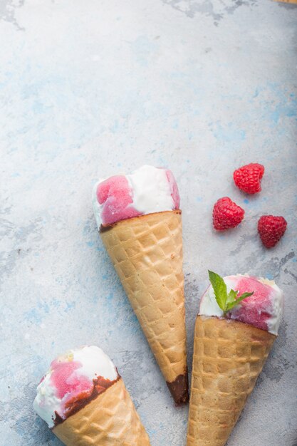 De kegelclose-up van het roomijs. Roze Roomijslepel in wafelkegel over concrete achtergrond. plat lag, om te bekijken. Aardbeien- of frambozensmaak. Zoete dessertclose-up,