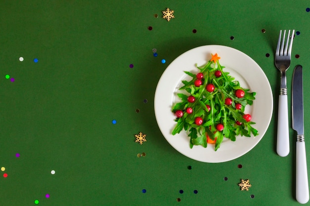 De kerstboomsalade op witte plaat op groen