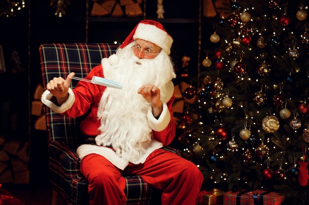 De kerstman draait een medisch masker in zijn handen