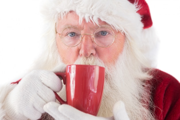 De kerstman drinkt van een rode kop