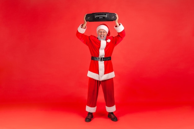 De kerstman heeft een opgewonden uitdrukking en houdt een bandrecorder boven zijn hoofd.