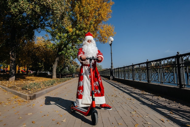 De kerstman heeft haast op een scooter met cadeautjes voor de vakantie aan de kinderen.