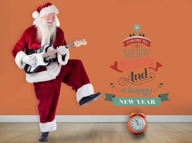 Foto de kerstman heeft plezier met een gitaar tegen een kamer met houten vloer