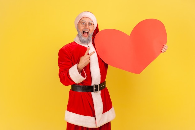 De kerstman houdt de mond open, toont een groot rood hart en een v-teken en viert vakantie.
