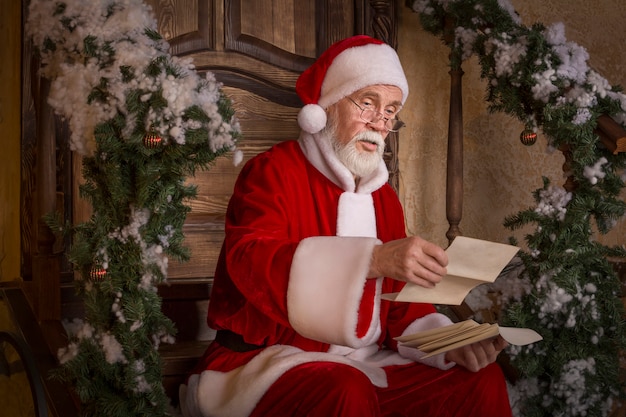 De Kerstman leest de letters op de veranda van het versierde huis.