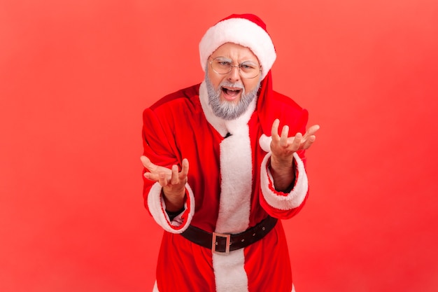 De kerstman staat met opgeheven handen en verontwaardigd agressief gezicht te vragen waarom.