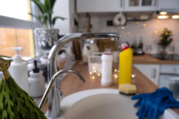 De keuken schoonmaken voor de kerst- en nieuwjaarsvakantie Wasmiddel droog poeder spons handschoenen zijn op de gootsteen Feestelijke inrichting in het witte keuken gezellige interieur van het huis