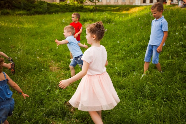 De kinderen in het park rennen achter de bubbels aan Leuke spelletjes met zeepbellen