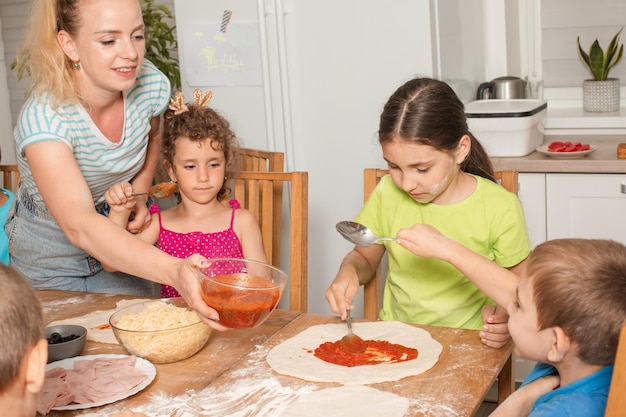 De kinderen met een leraar bereiden pizza in de keuken