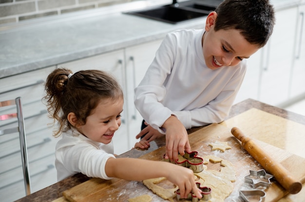 De kinderen snijden de vormstukken voor het deeg uit het deeg