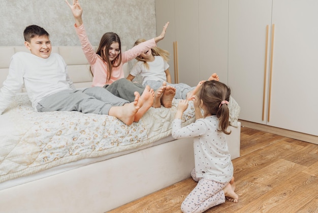 de kinderen zijn in een deken gewikkeld en kietelen elkaar de hielen op het bed gezin heeft plezier thuis vrije tijd