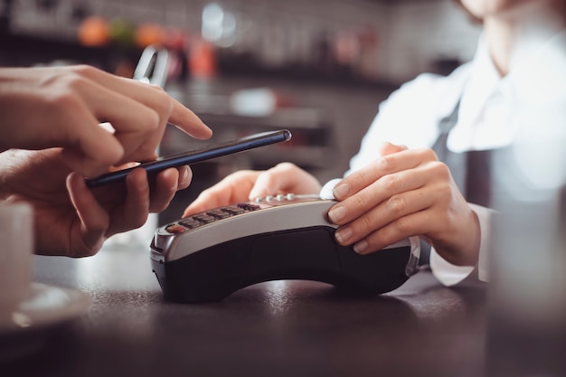 De klant betaalt in het café met een mobiele telefoon met behulp van NFC-technologie