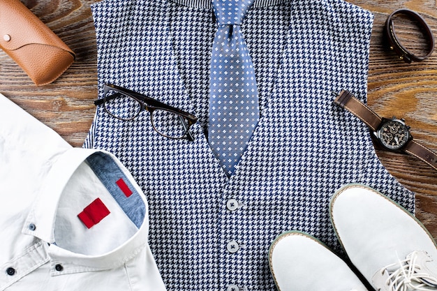 De klassieke kledingoutfit van de mens lag plat met formeel shirt, vest, stropdas, schoenen en accessoires