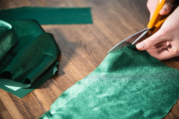 De kleermaker knipt de groene doek op tafel met een schaar.