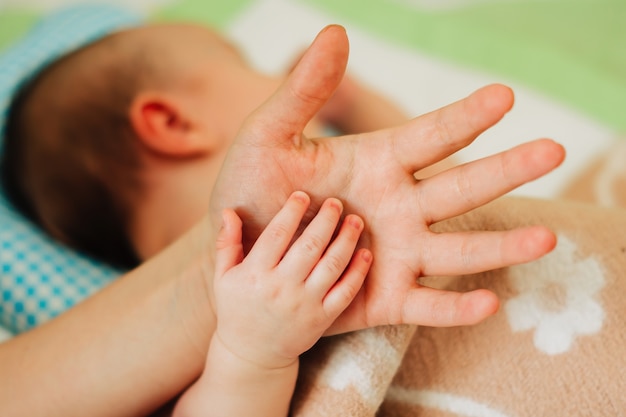 De kleine hand van de baby ligt op de hand van de ouder.