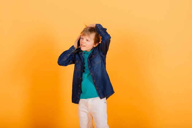 De kleine jongen belt op de gele muur