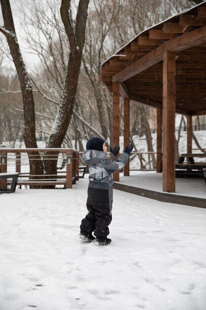 De kleine jongen die plezier heeft met de sneeuw. Wintertijd. De jongen is blij.