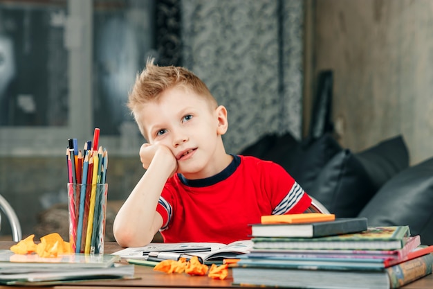 De kleine jongen is verdrietig, verveeld om huiswerk te maken.