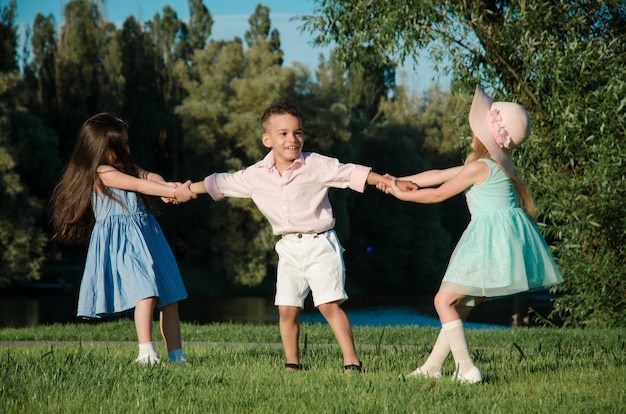 De kleine kinderen spelen rond op het grasveld. twee meisjes en een jongen