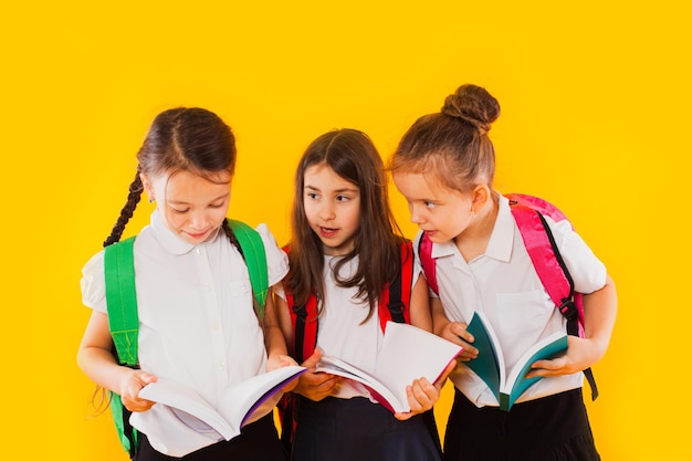 De kleine schoolmeisjes lezen de boeken op de gele achtergrond