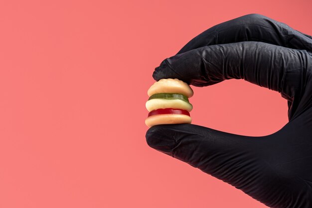 De kleurrijke suikergoedhamburger met dient zwarte handschoen in.