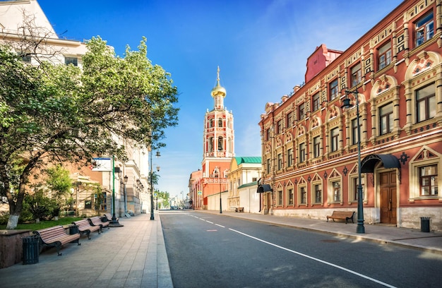 De klokkentoren van het Petrovsky-klooster in Moskou en banken onder de bomen