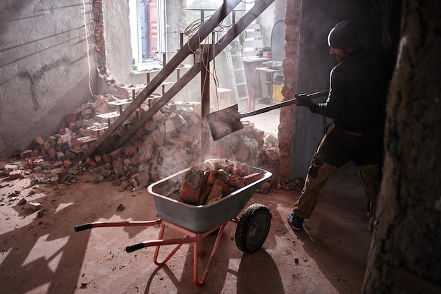 De klusjesman bouwt een huis, breekt de muren af en zet bakstenen in een bouwschop in bakstenen, het reparatieproces